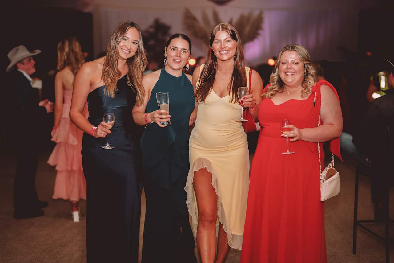 Four women in formal dresses pose for the camera. 