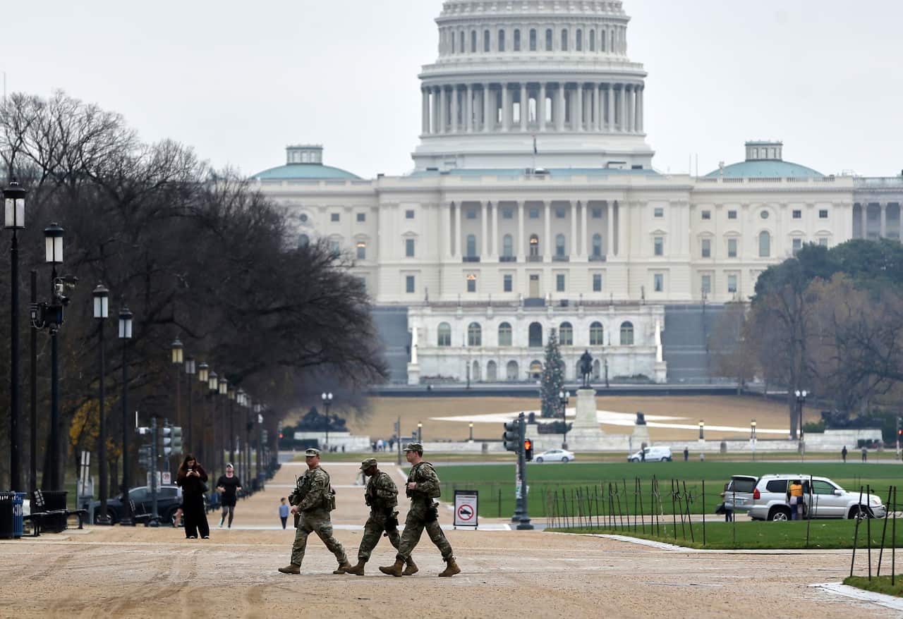 National guard troops in uniform patrolling near a large building.