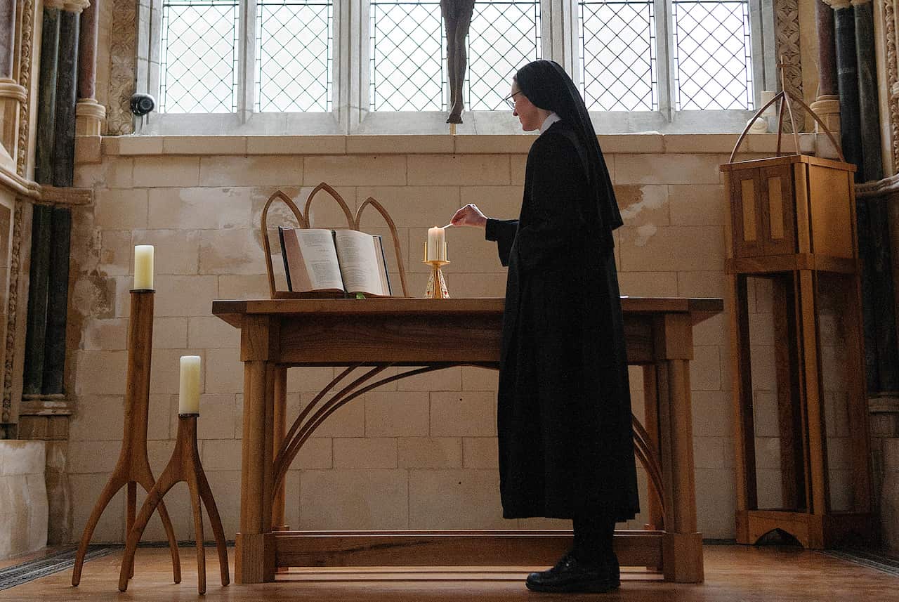 6.17 Sr Jeanne OSB lighting altar candle in the neo-Gothic Church at Kylemore Abbey crop.jpg