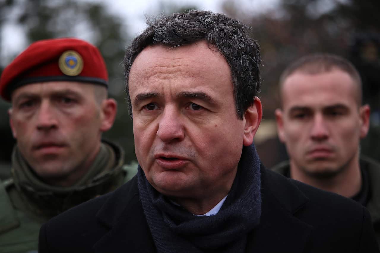 Prime minister of Kosovo flanked by men in military garb