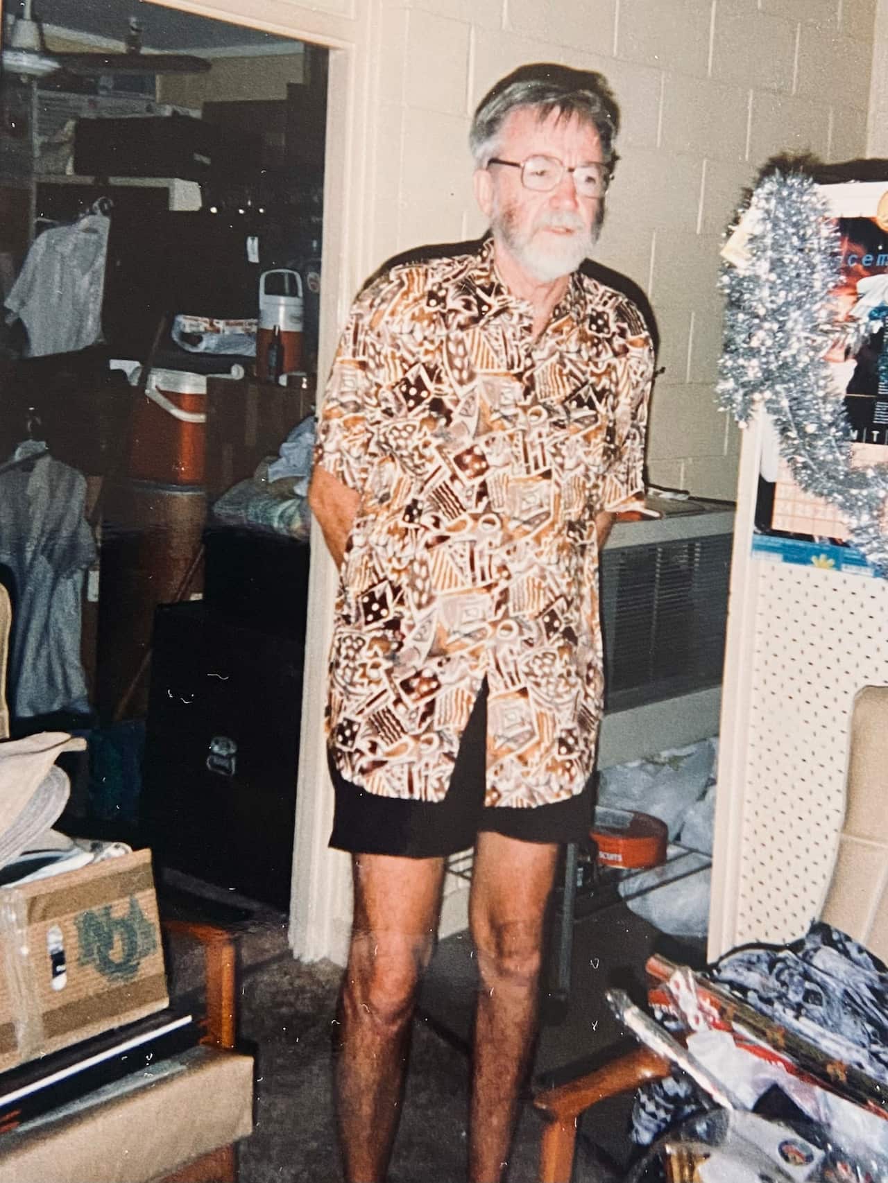 an older man with a grey beard and hair in a crowded apartment