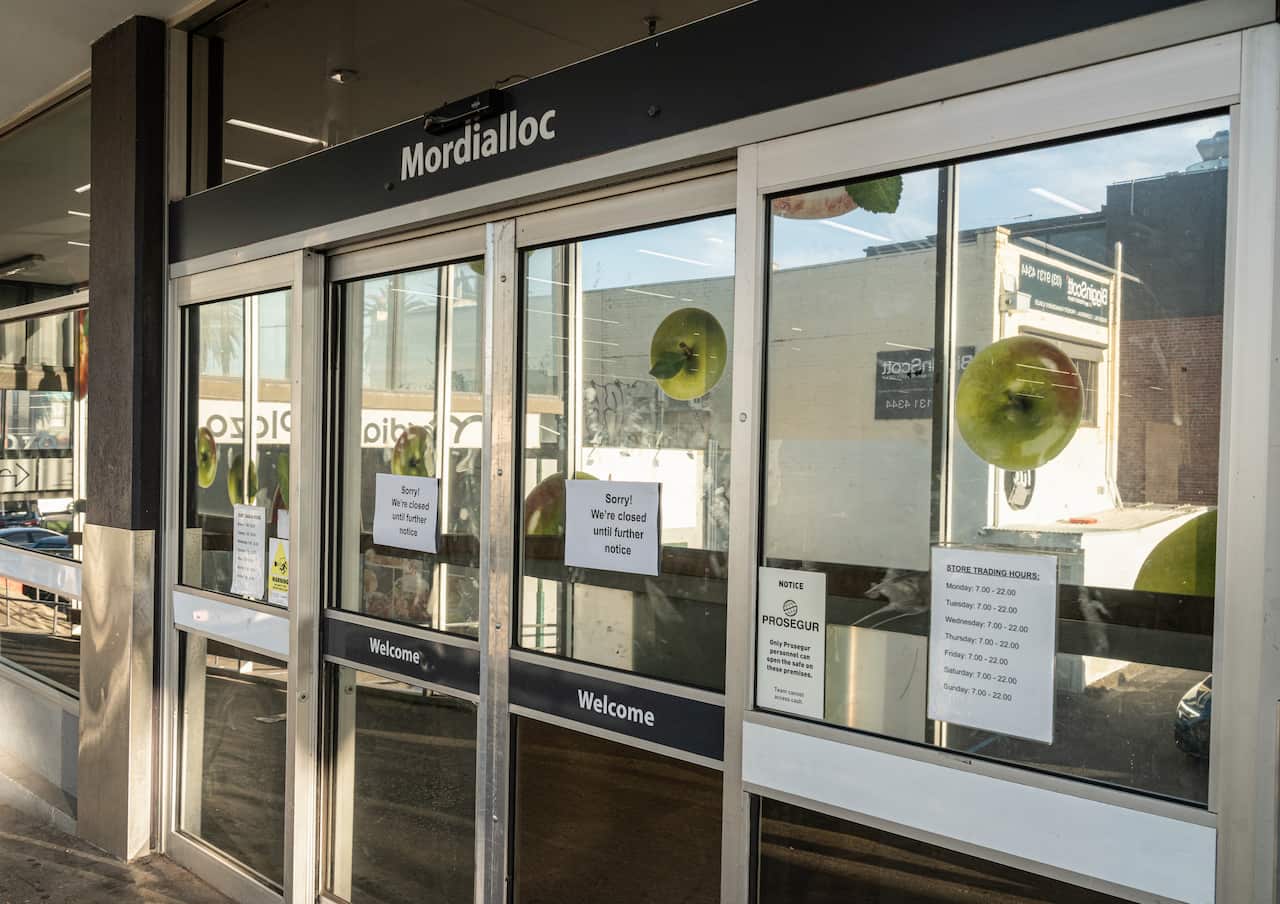  A shopfront with notices on its glass doors saying it is closed until further notice