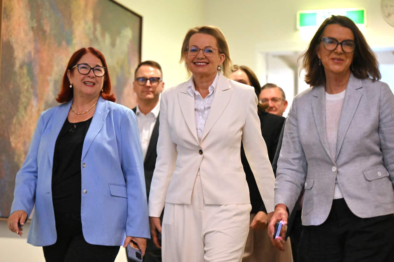 Three women smiling as they walk down a corridor 