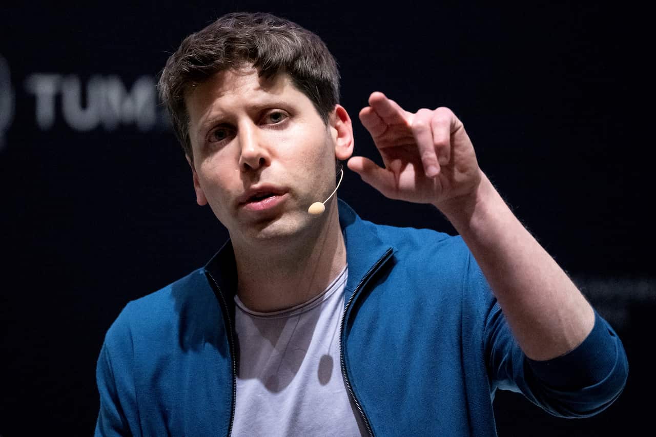 A man gestures as he speaks through a mic