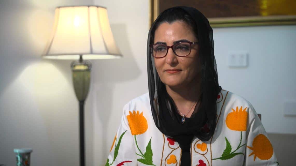 A woman wearing glasses and a black head scarf.