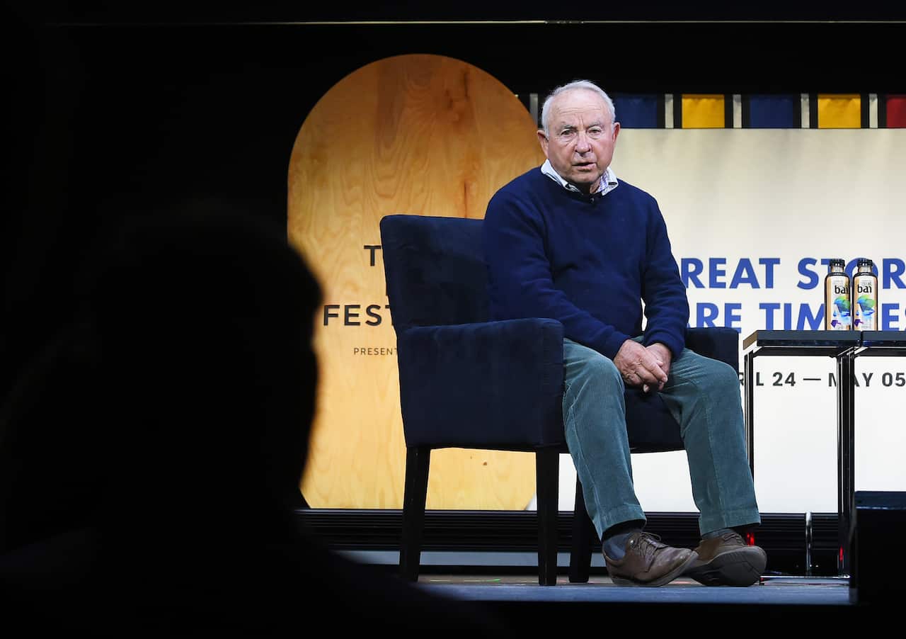 Yvon-Chouinard sitting in a chair speaking on stage.