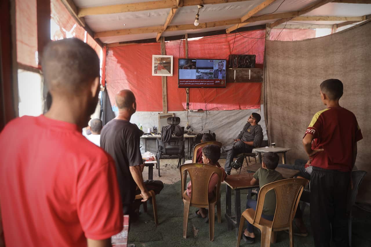 Gazabs watch a television which is broadcasting news of the ceasefire agreement.