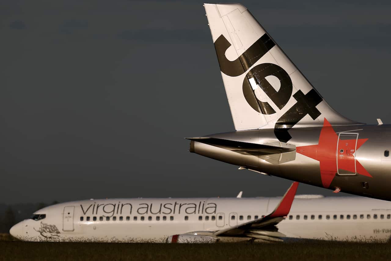 A Virgin Australia plane in the background, with the rear of a Jetstar plane in the foreground. 