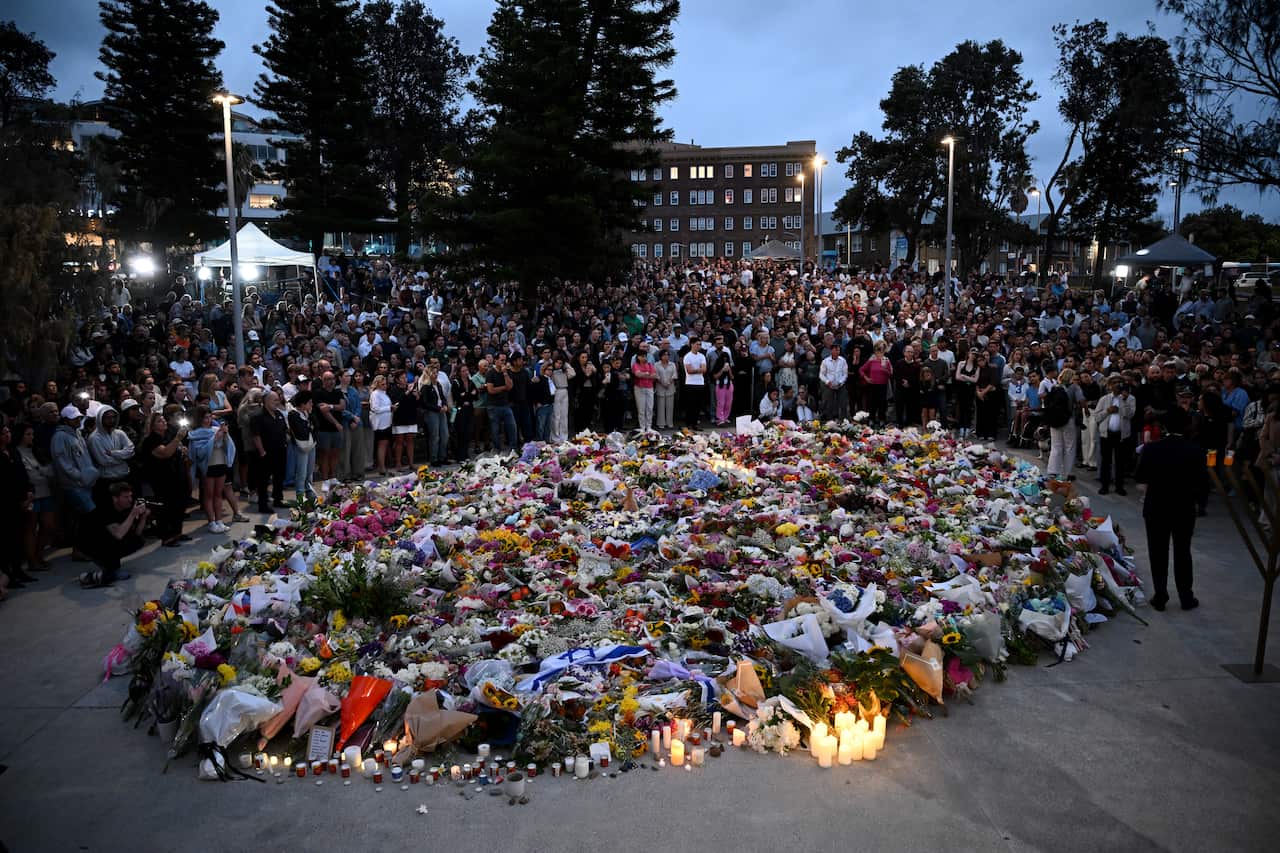 Mourners pay their respects at a vigil of flowers and candles in Bondi Beach
