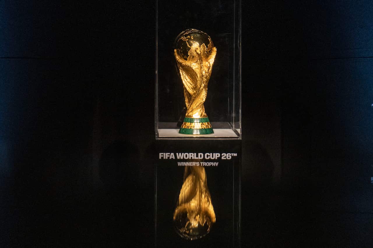 A gold FIFA World Cup trophy encased in a glass box. 