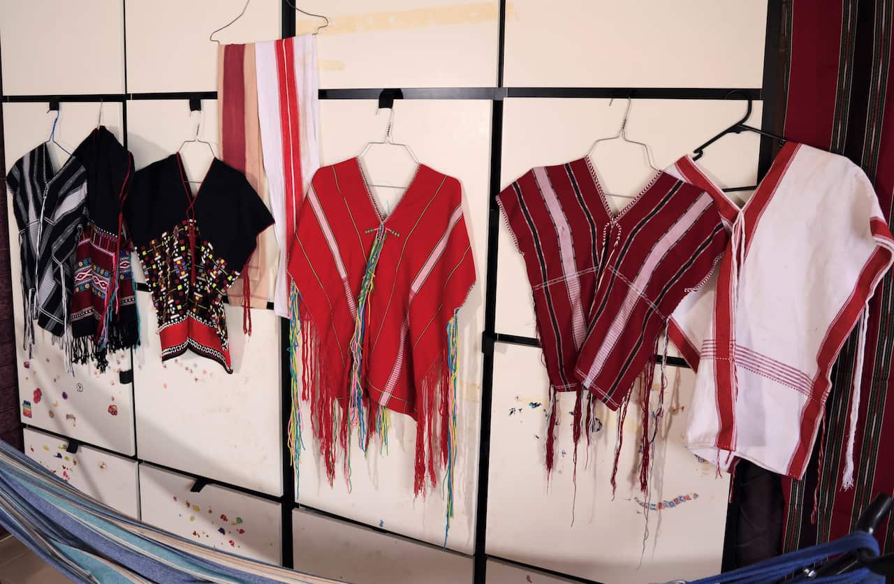 A selection of colourful clothing hangs on a wall.