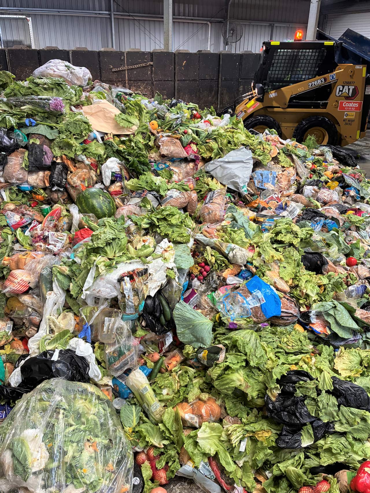 A mound of food waste including green vegetables and bread.