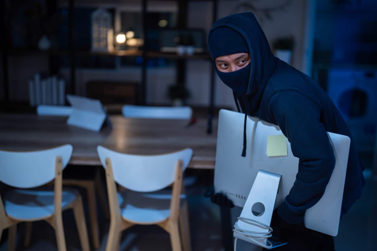 Man burglar stealing tv set from house