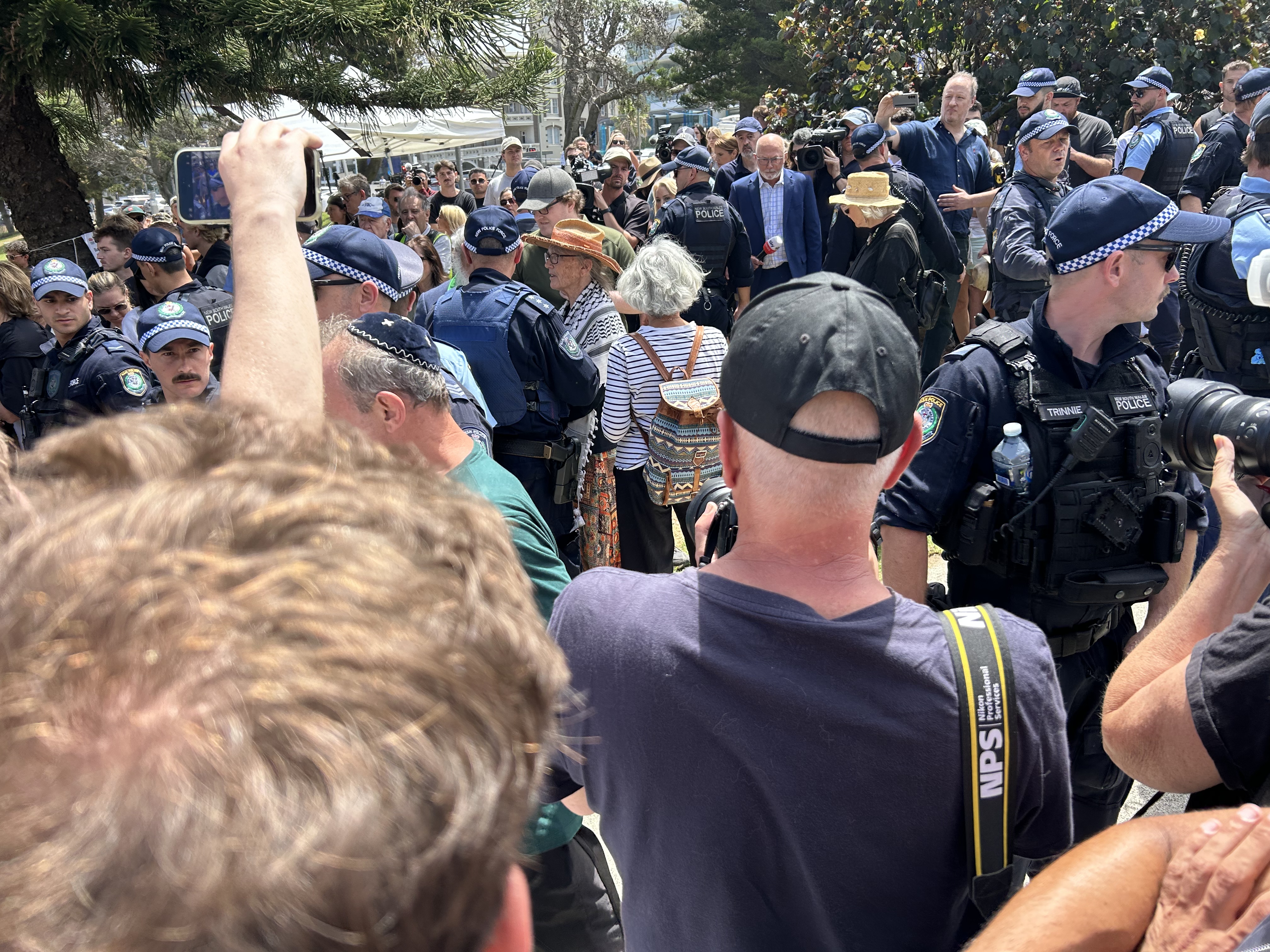 A woman wearing a hat and keffiyeh scarf speaks to police. 