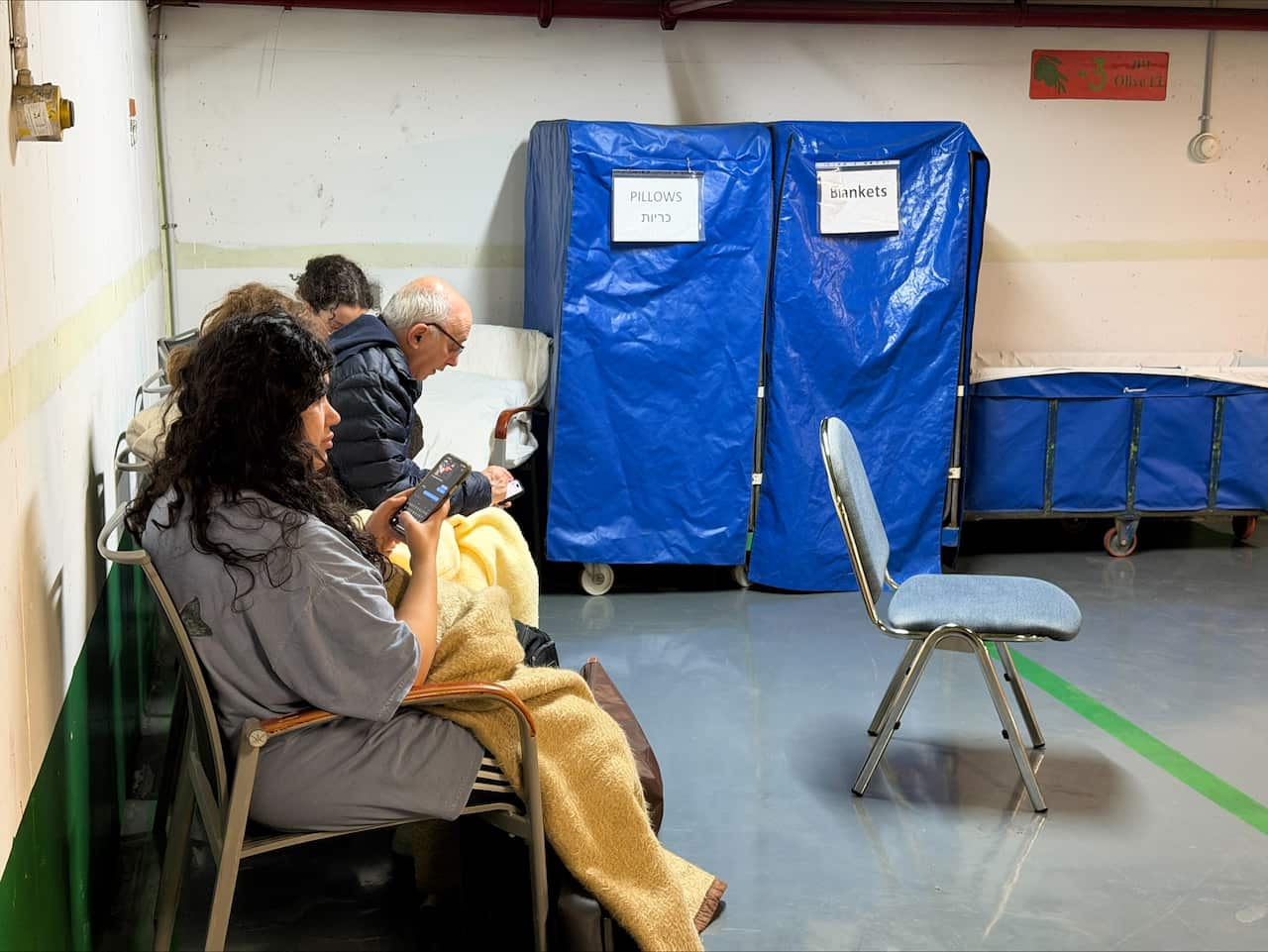People sitting on chairs inside an underground carpark.