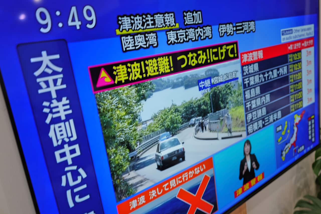 A TV screen showing Japanese characters with a picture of a car moving on a road in the centre against a striking blue background.