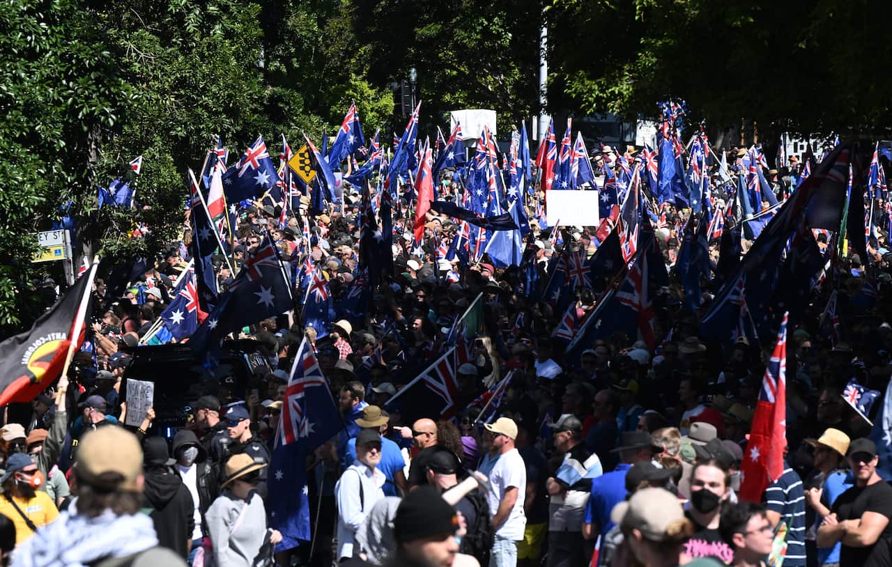A large crowd of people, many of whom are holding Australian flags.