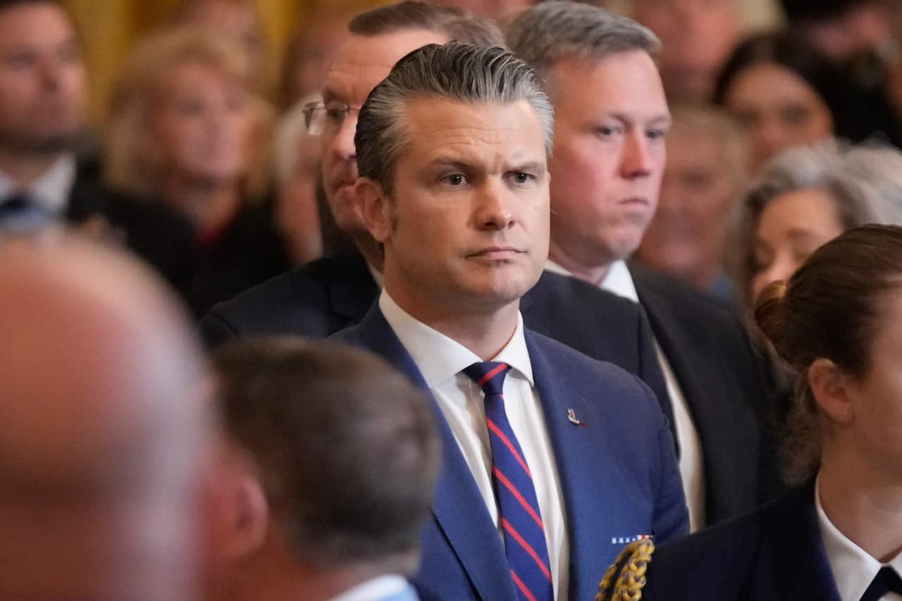 A man in a tie stands among a crowd.