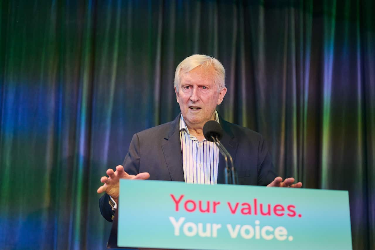 An elderly man is speaking at a lectern with the words "Your values, your choice" written on it.