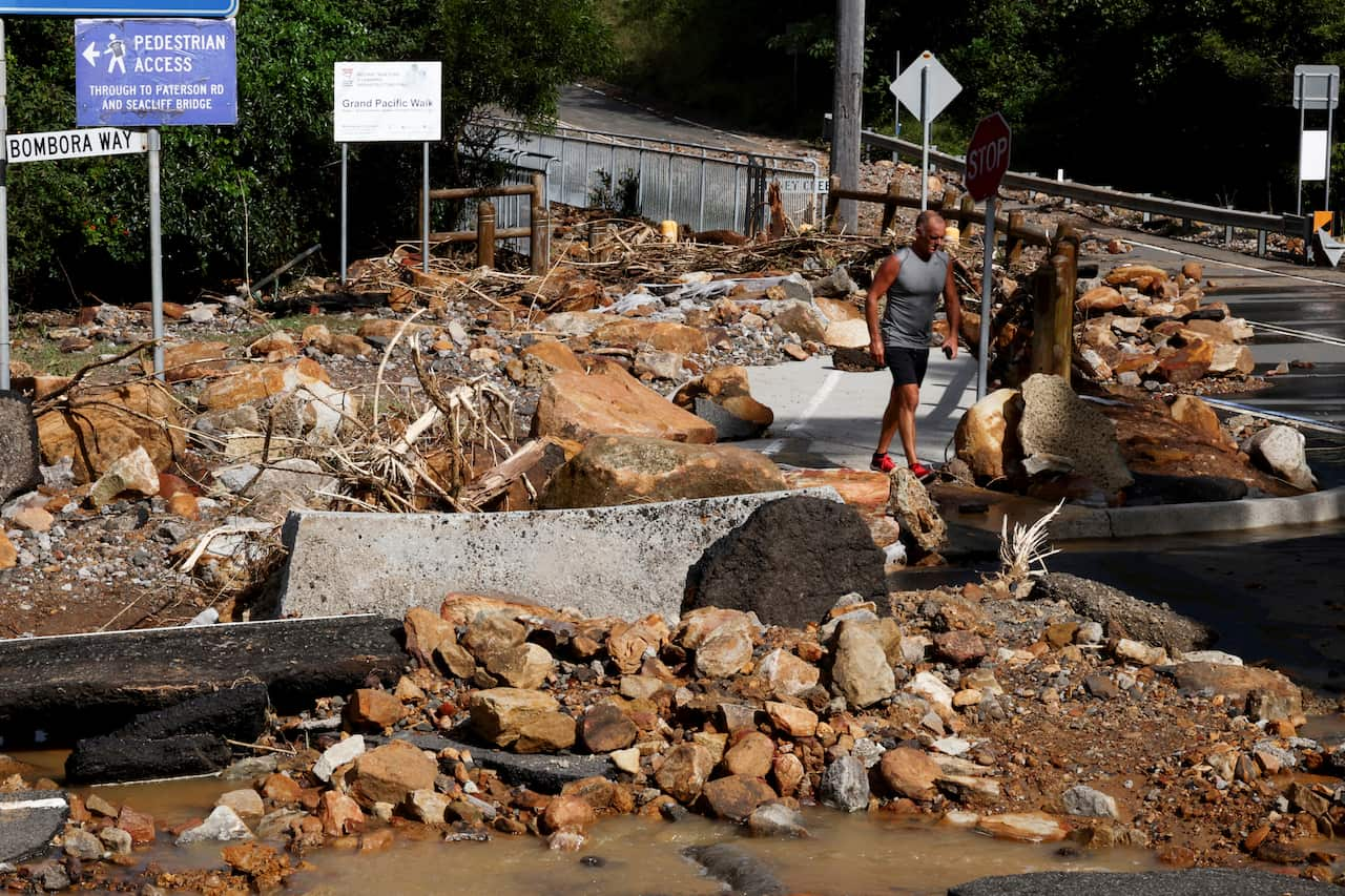 A man walks over fallen rocks and debris from a landslide