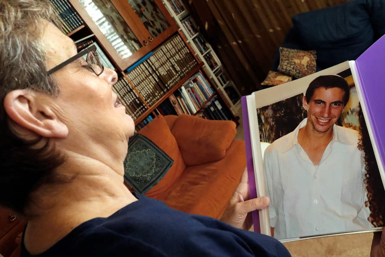 A woman looks at a photo in a photo album which she is holding