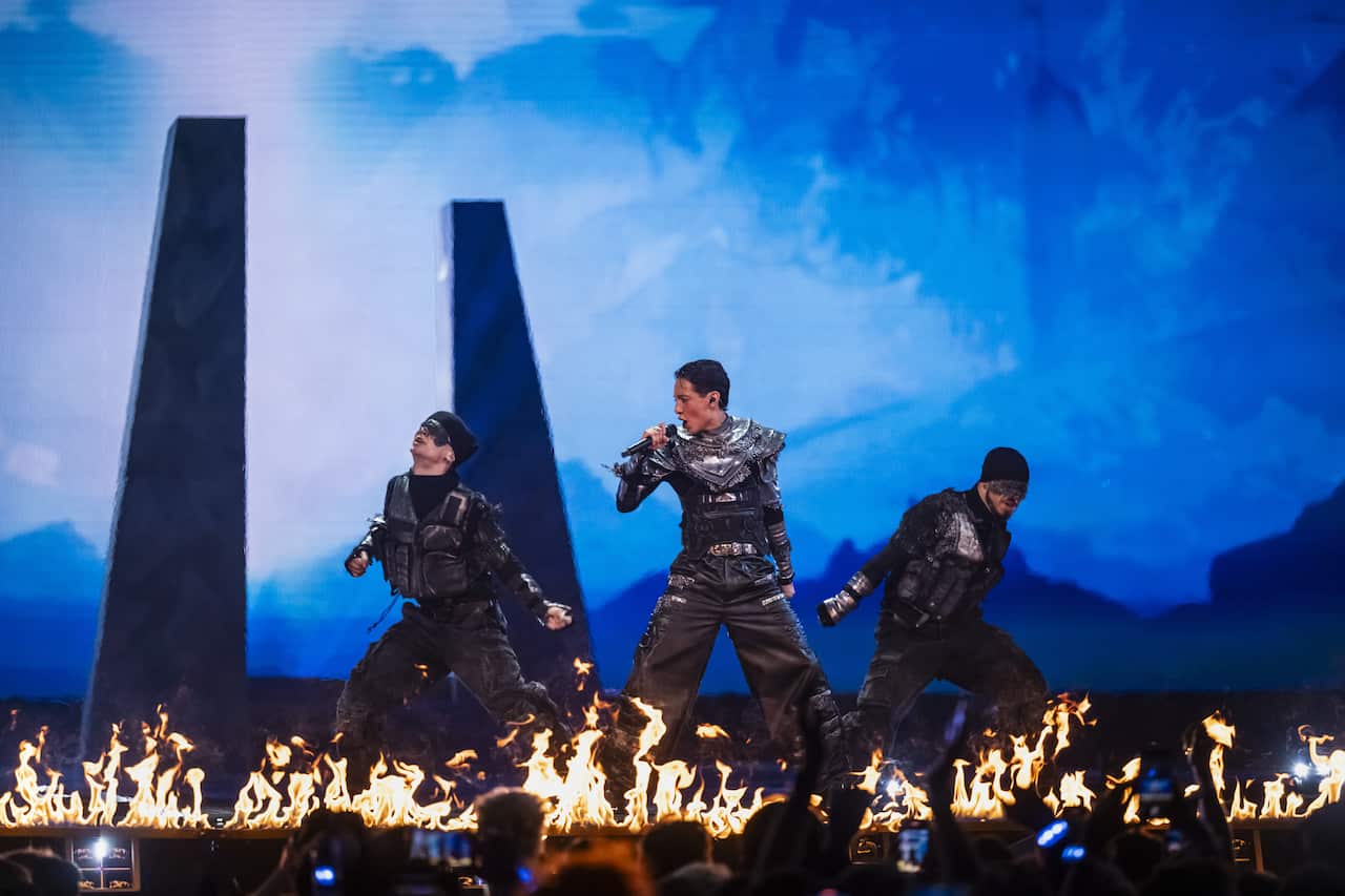 Three performers on stage with flames