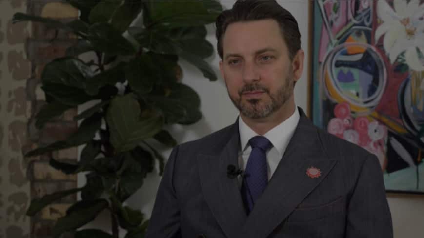 A middle-aged man in a dark grey suit.