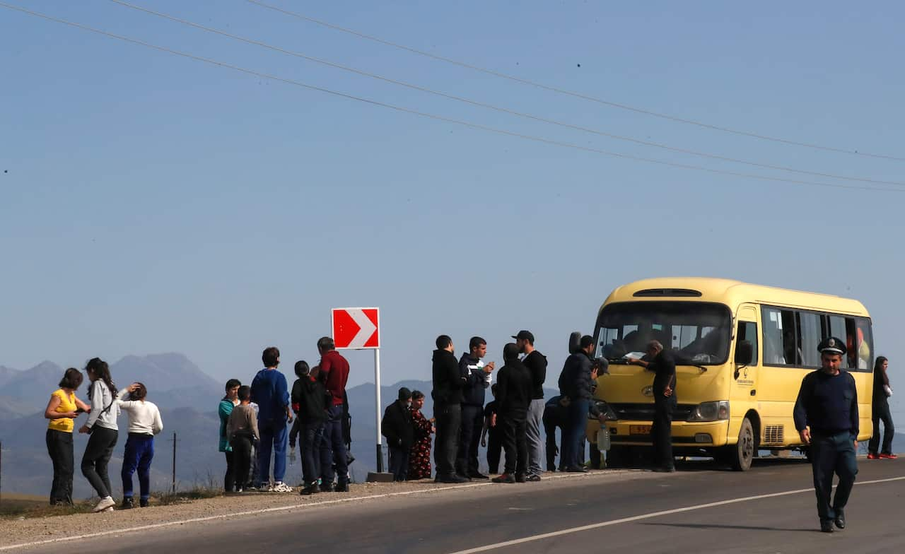 A number of people wait to board a yellow bus during a mass exodus of Armenians out of Nagorno-Karabakh.