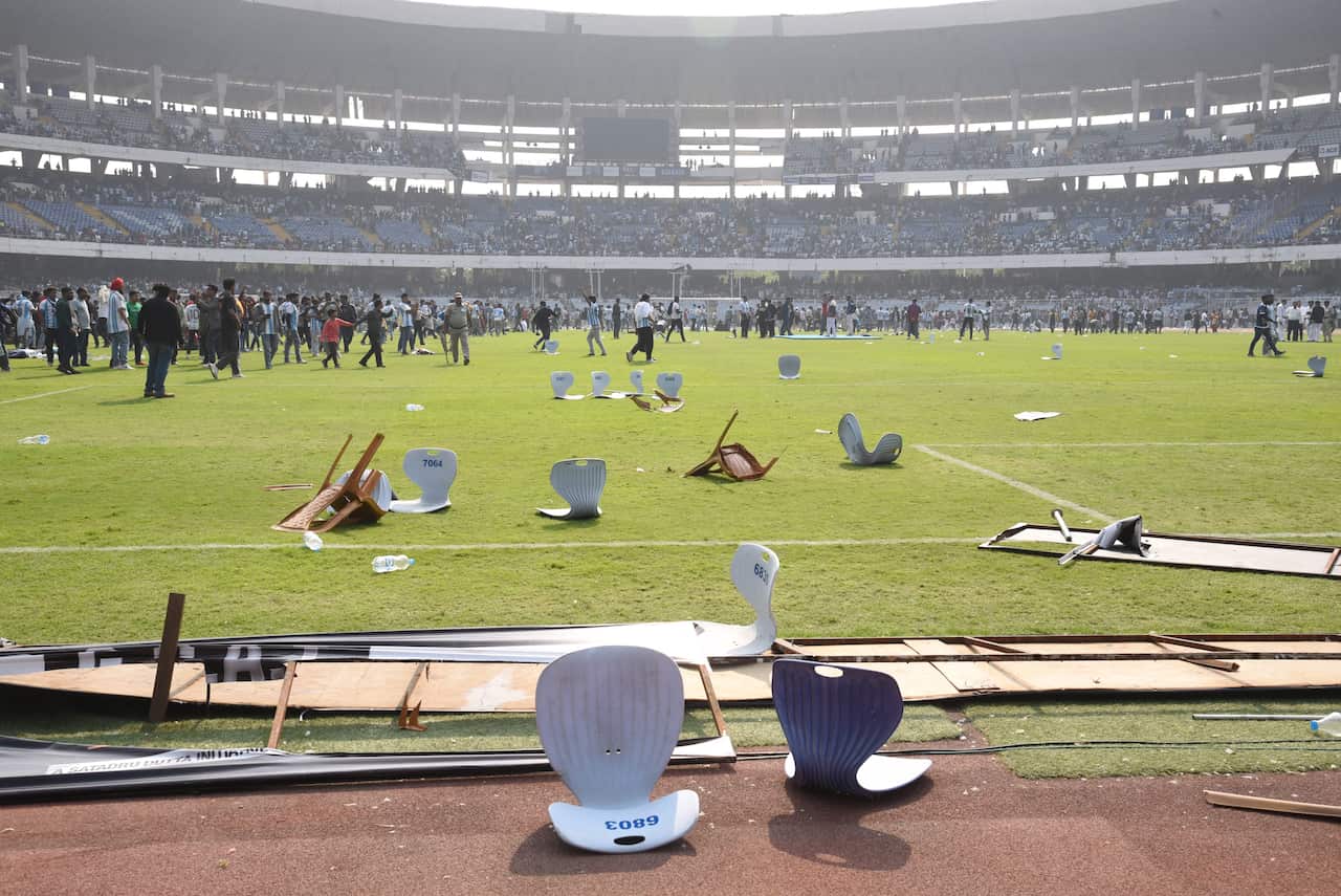 Chairs scattered across a football pitch as crowds storm the field