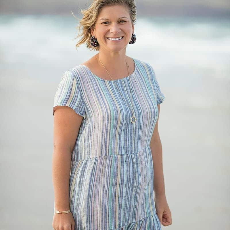 A woman smiling on a beach.