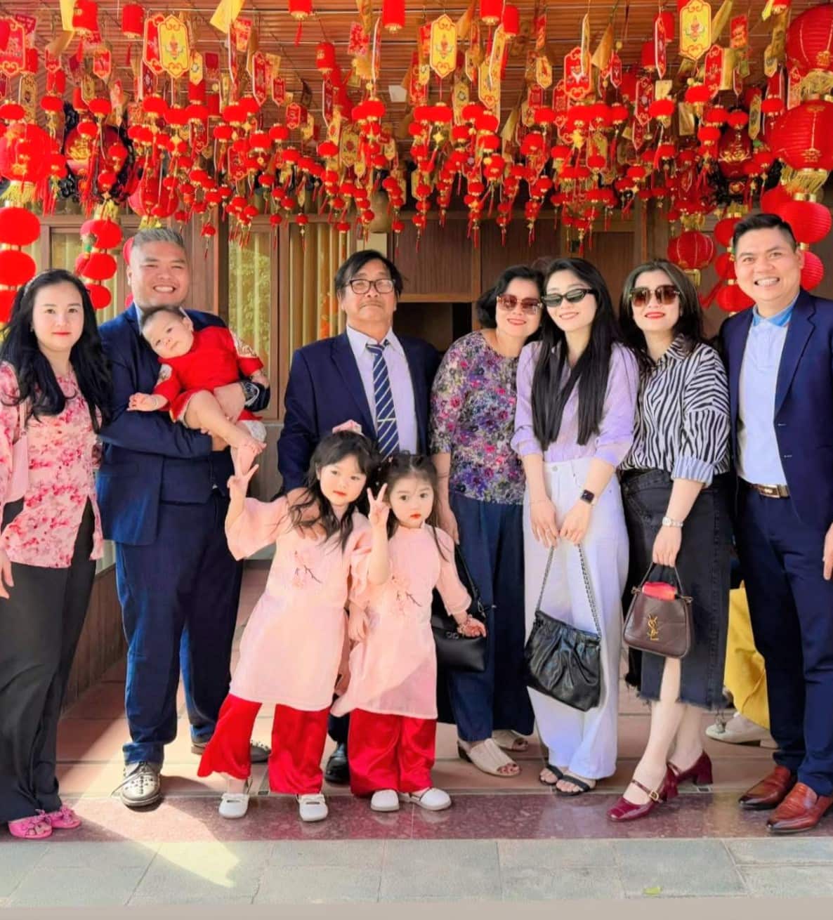 A family group stand together under bright red lanterns.