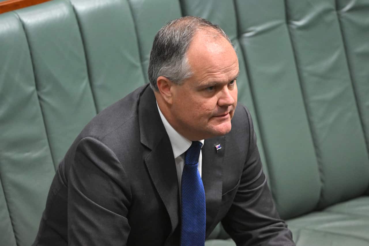A man in a suit sitting on a green padded bench