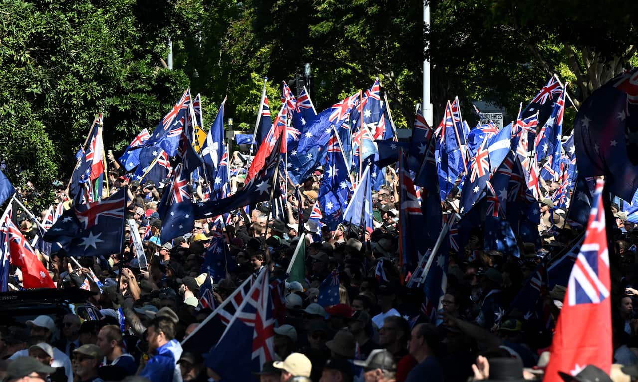 A large crowd, many of whom are waving Australian flags.