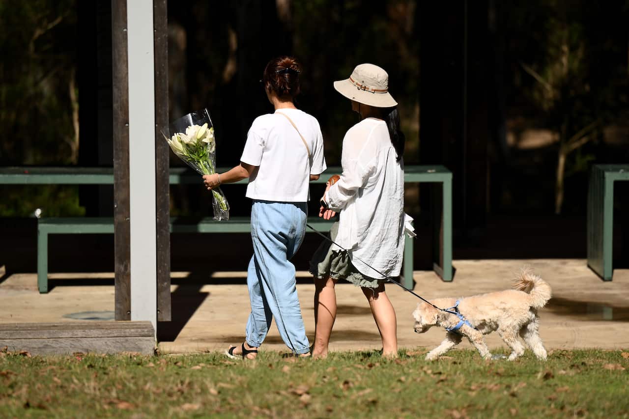 Women laying flowers at the scene of a stabbing