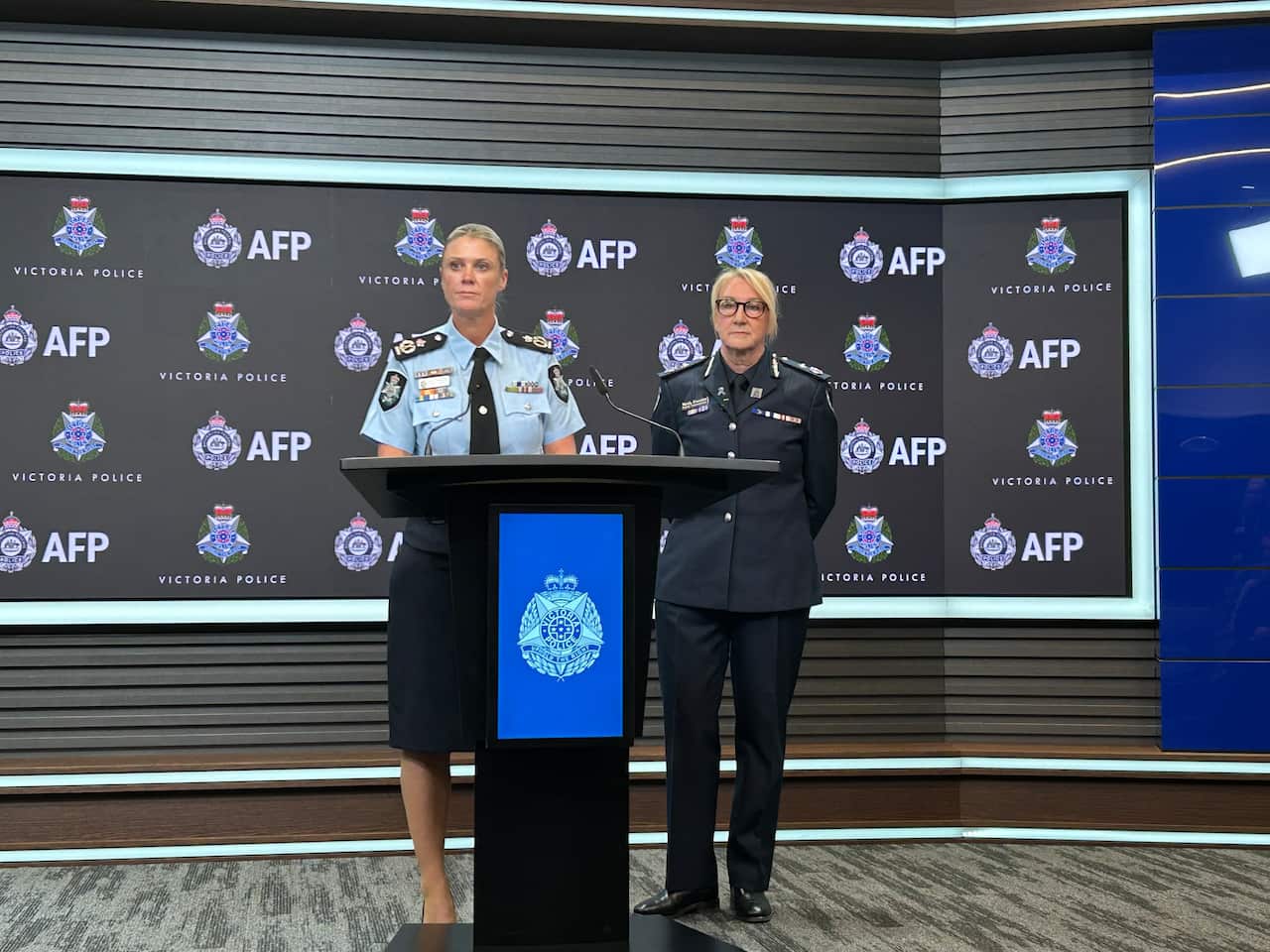 Two women in police uniform stand at a lectern during a media conference in front of a black background with AFP and Victoria Police logos.