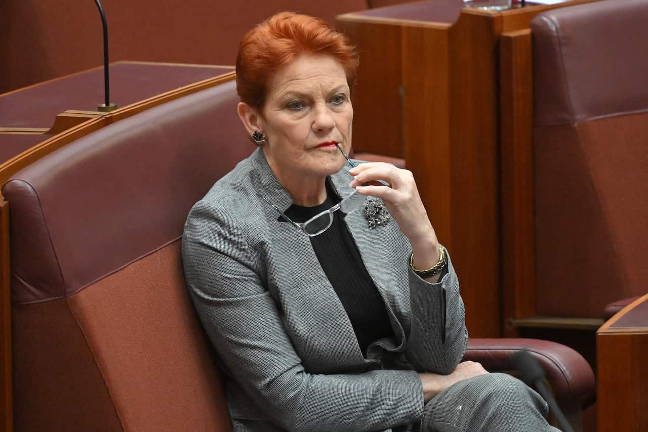 A woman in a grey suit sitting on a red bench seat