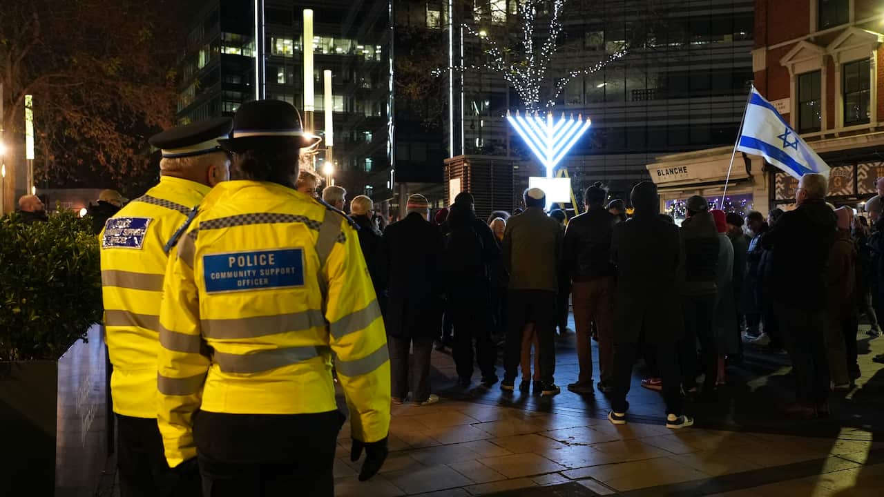 Two police officers in hi vis jackets stand near a crowd.