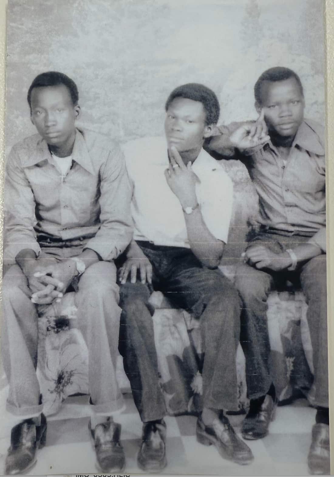 Three men sit next to each other for a photo 