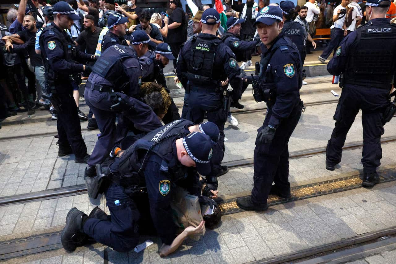 Uniformed police detaining a person on the ground