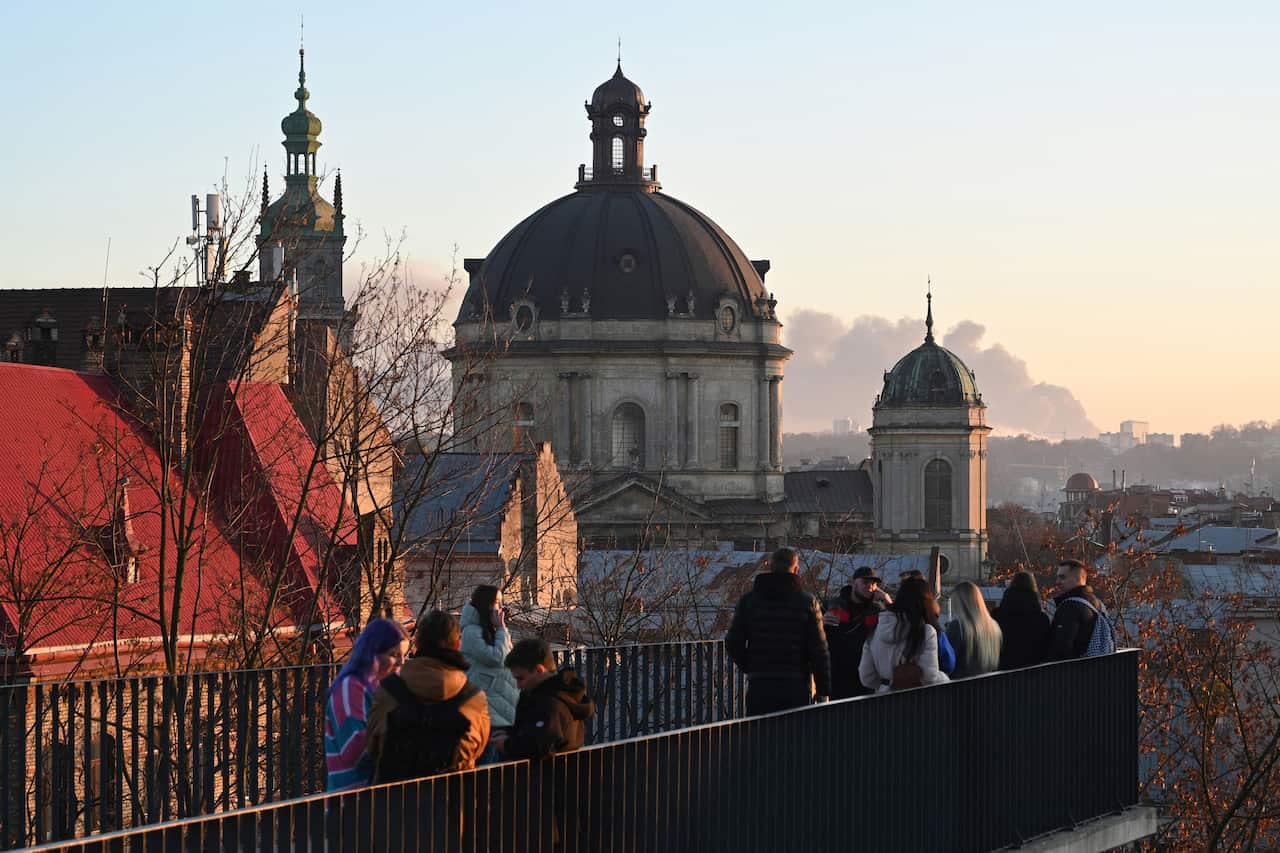 Residents in Lviv observe smoke billowing from a missile strike in the distance