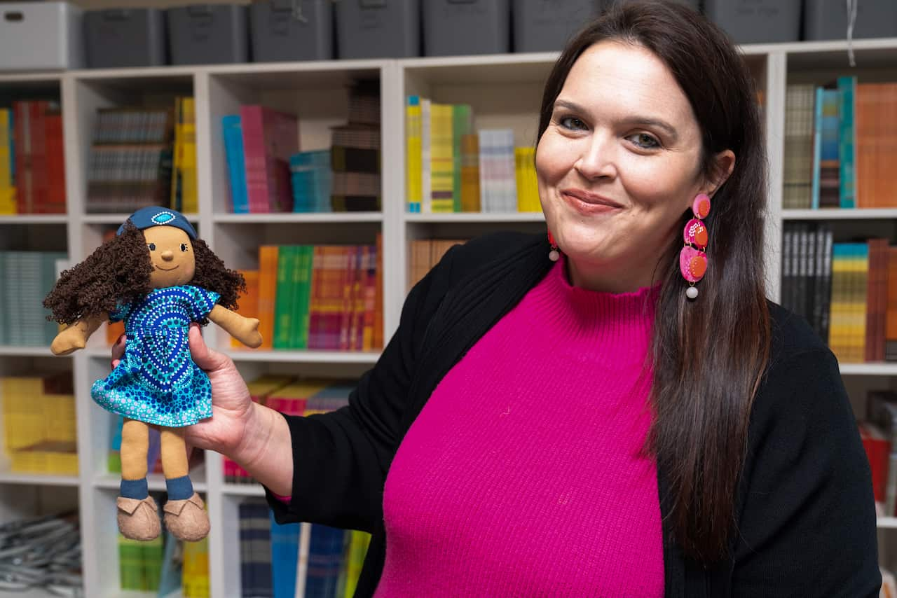 A woman holds up a small doll