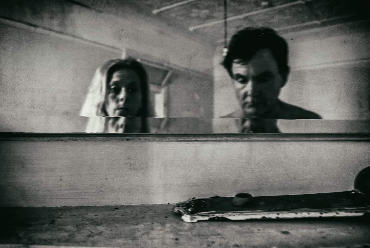 a black and white photo of a woman and a man in an empty room of a run-down building