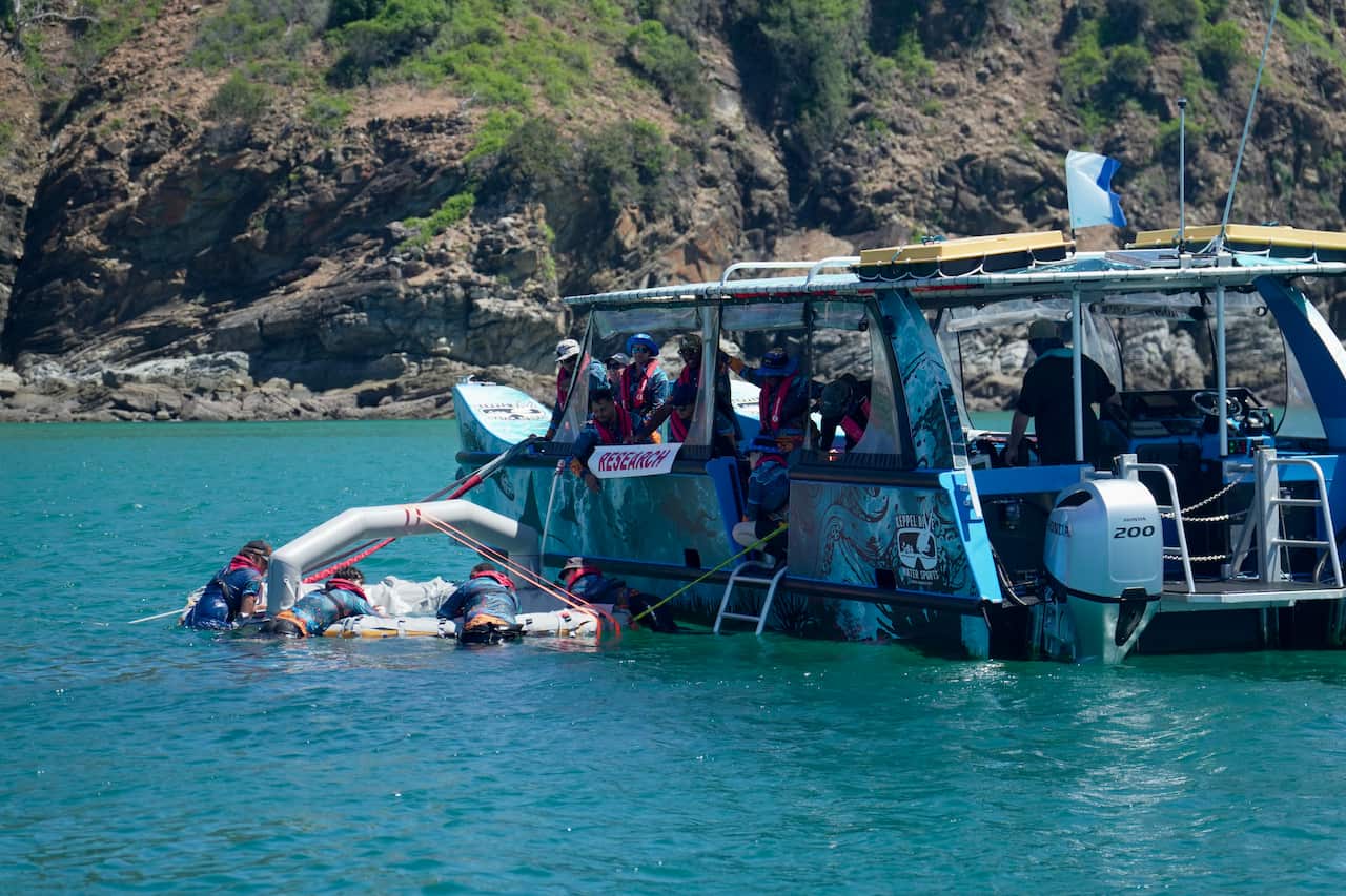 people on boat jumping into water with an inflatable pool
