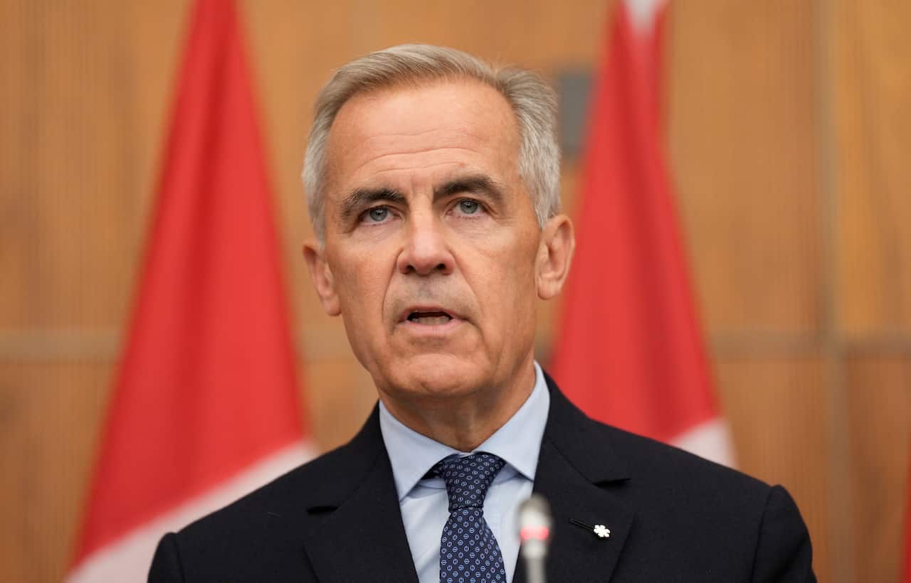 A man in a dark suit speaks with the media during a news conference.