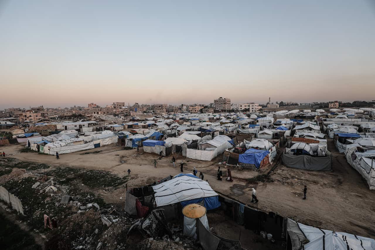 An aerial shot of rows of makeshift tents pitched on dirt roads amid the rubble.