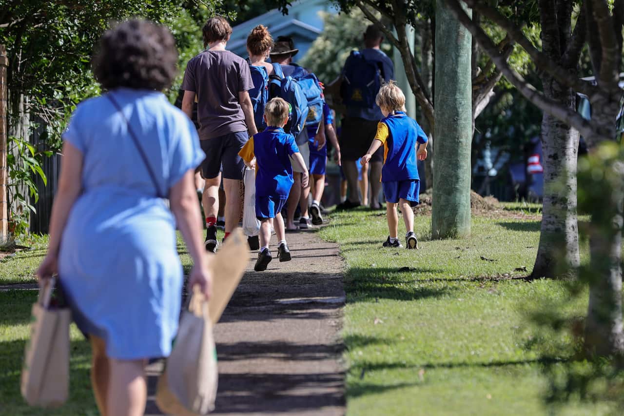 Primary school students and their parents walk along a street