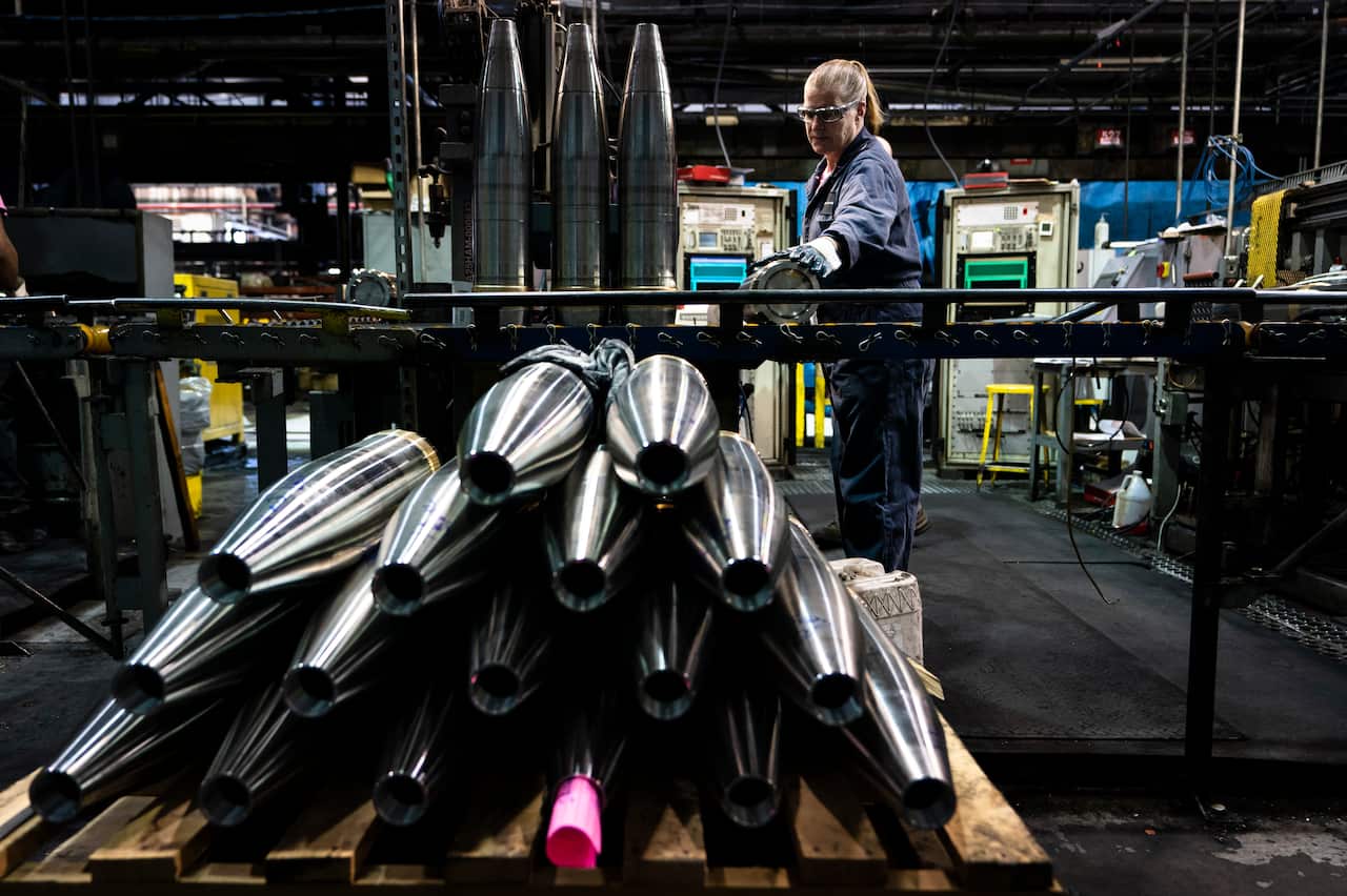 A steel worker inspects artillery projectiles on the production line.