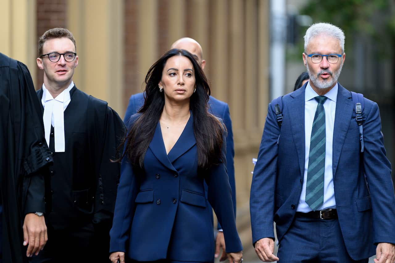A woman in a dark blue blazer walks in the centre of a group of men