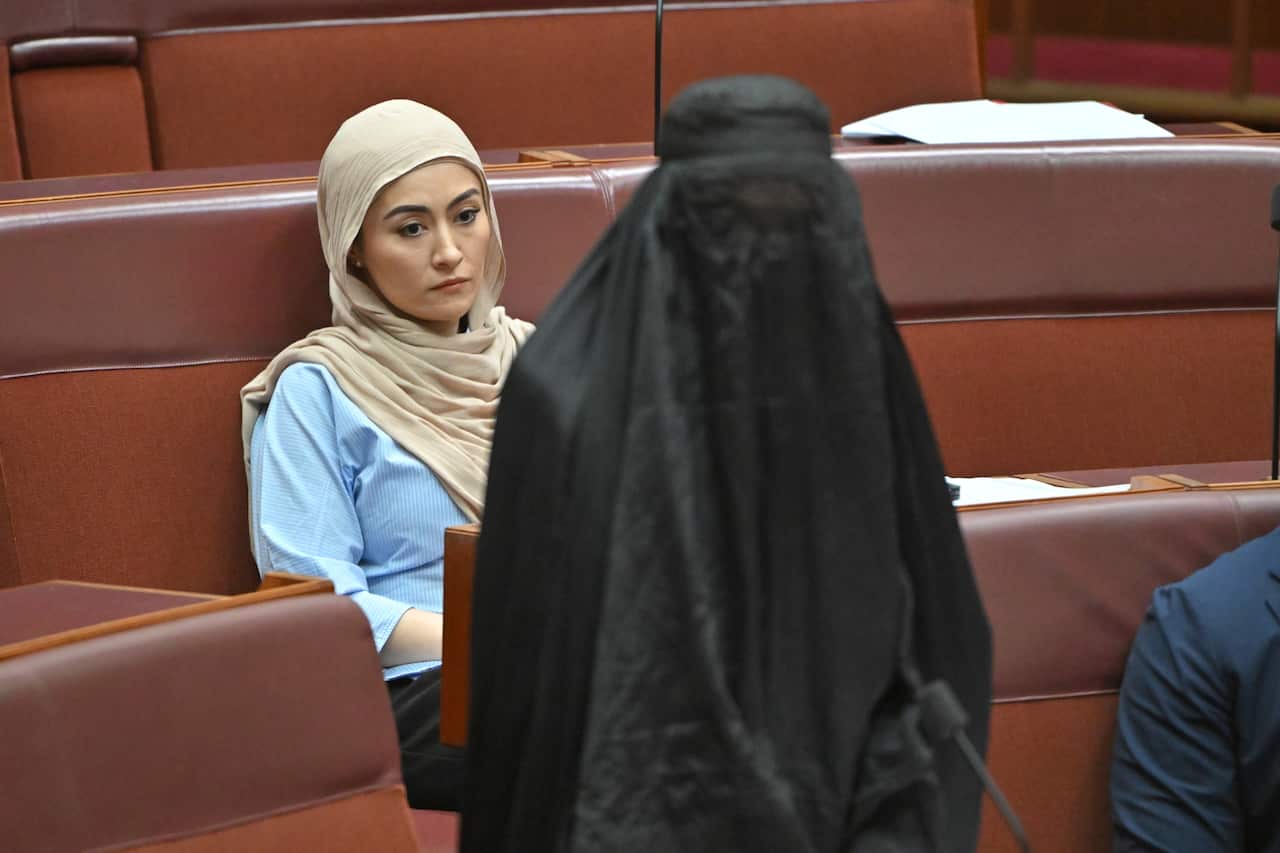 A woman in a burqa stands in the parliament.