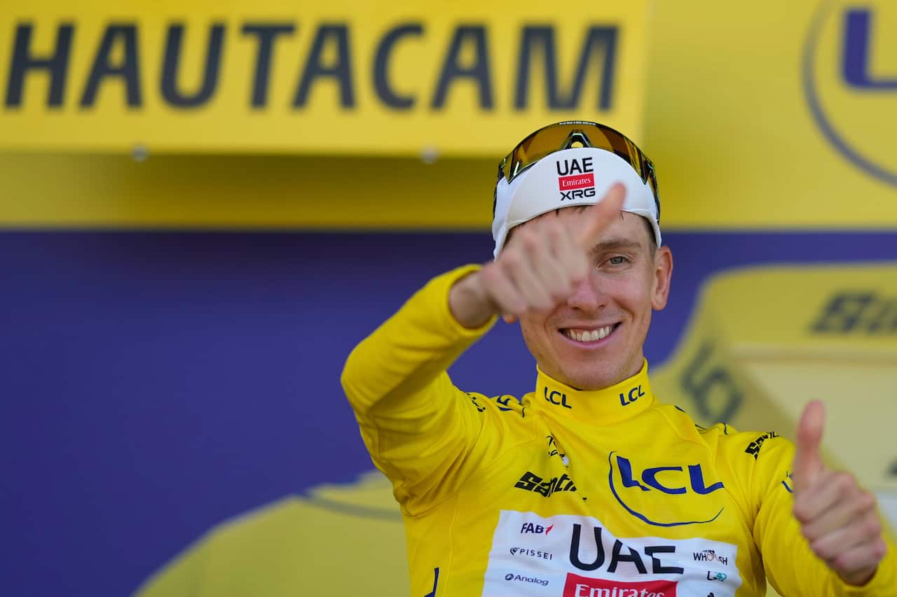 A man wearing a yellow cycling jersey smiling and giving thumbs up